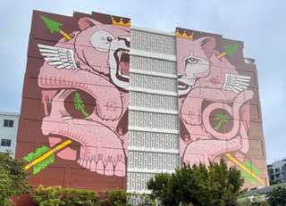 Wall art of pink lions separated by a building